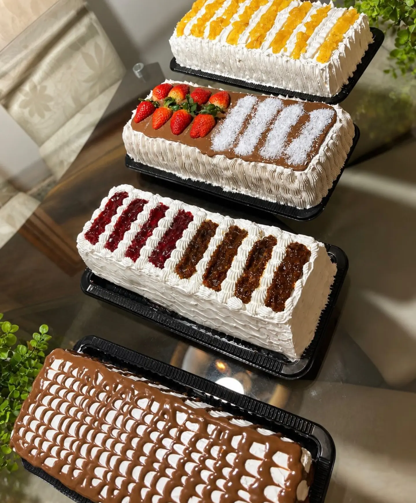 Quatro bolos retangulares decorados com frutas e coberturas de chocolate